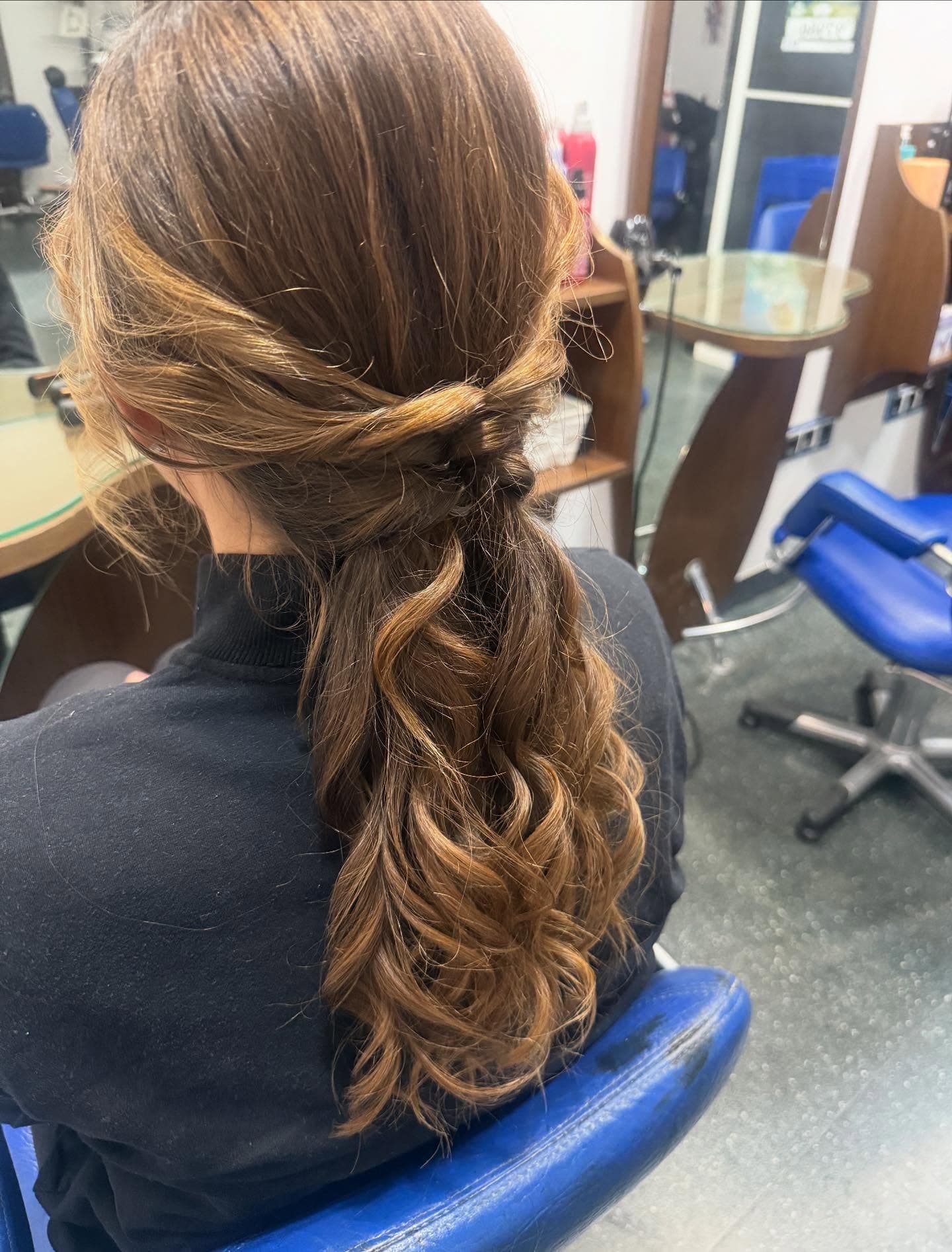 Cabello castaño ondulado con un peinado semirecogido elegante, visto desde atrás en un salón.